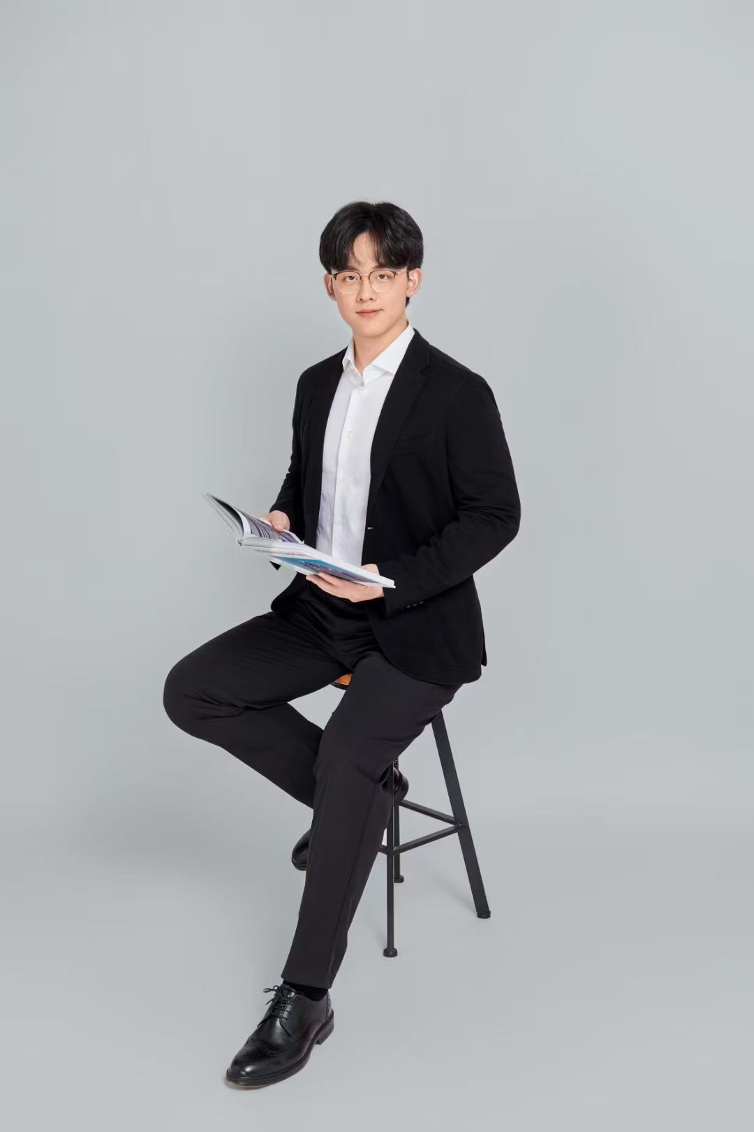 Zachary Wen holding a publication magazine in a studio portrait